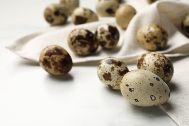 Many speckled quail eggs on white table. Space for text