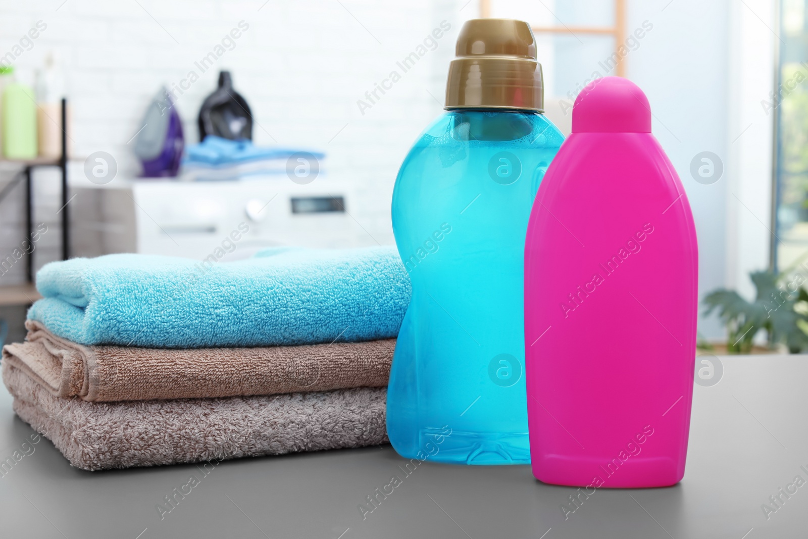 Photo of Stack of clean towels and bottles with detergents on table in bathroom