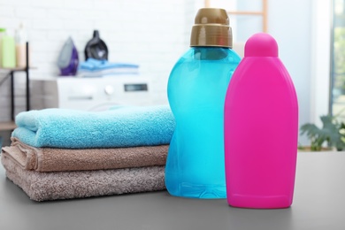 Photo of Stack of clean towels and bottles with detergents on table in bathroom