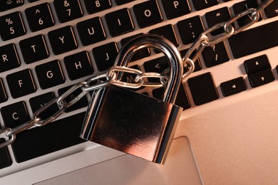 Photo of Cyber security. Padlock with chain on laptop, top view