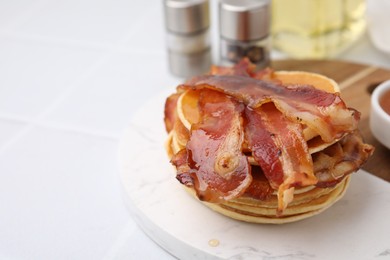 Delicious pancakes with bacon and honey on white table, closeup. Space for text