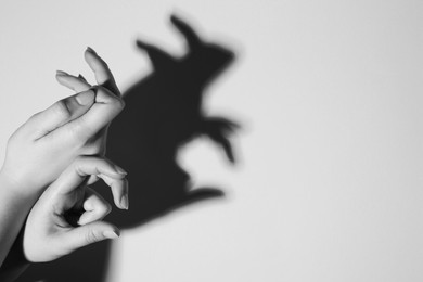 Shadow puppet. Woman making hand gesture like rabbit on light background, closeup with space for text. Black and white effect