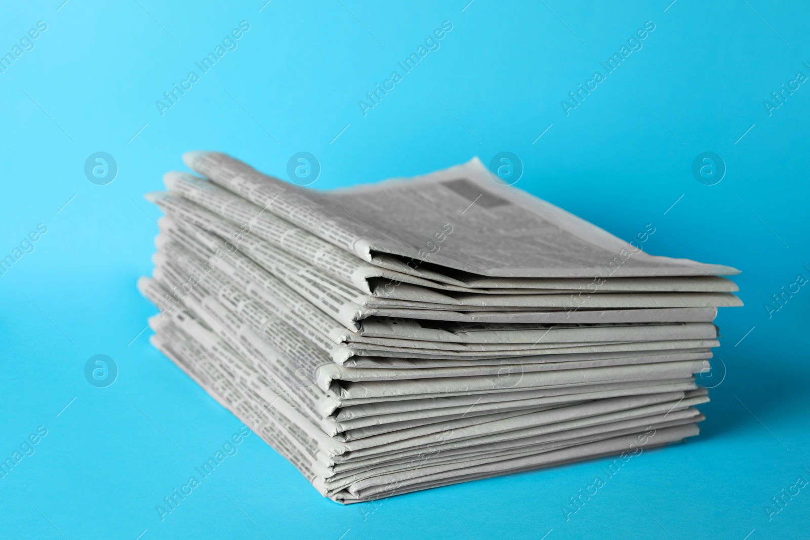 Photo of Stack of newspapers on light blue background. Journalist's work