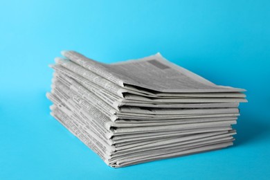 Stack of newspapers on light blue background. Journalist's work