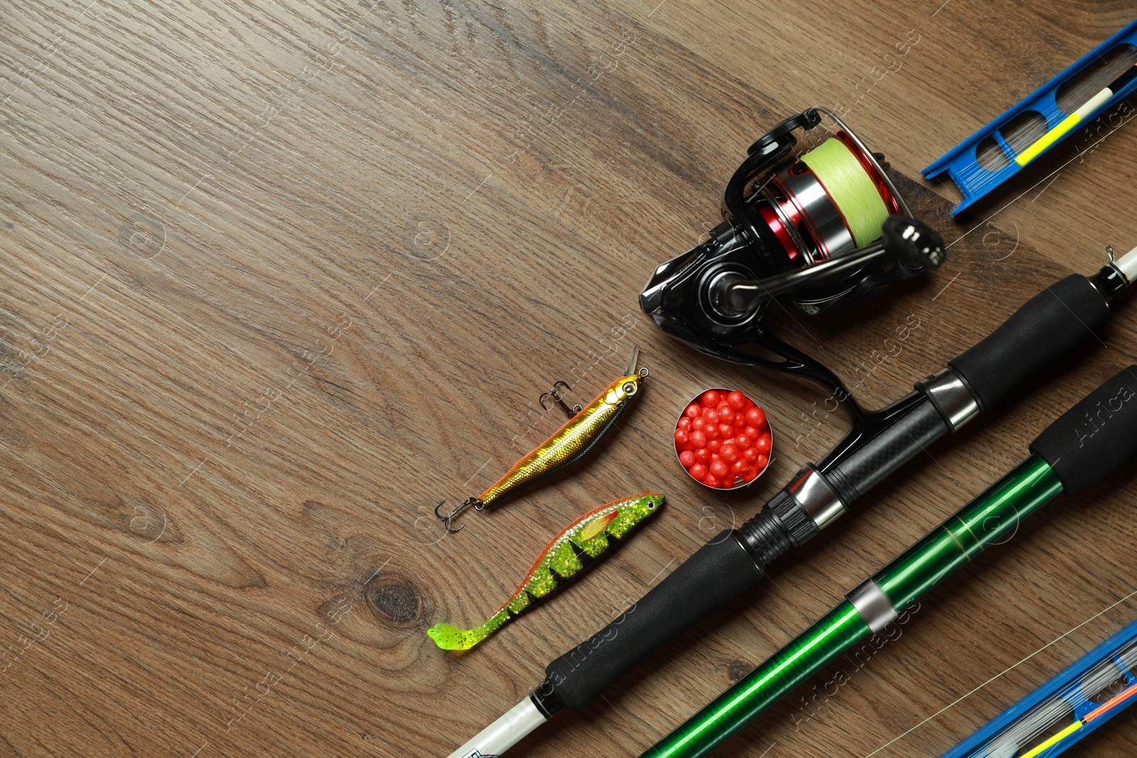 Photo of Spinning rods and fishing tackle on wooden background, flat lay. Space for text