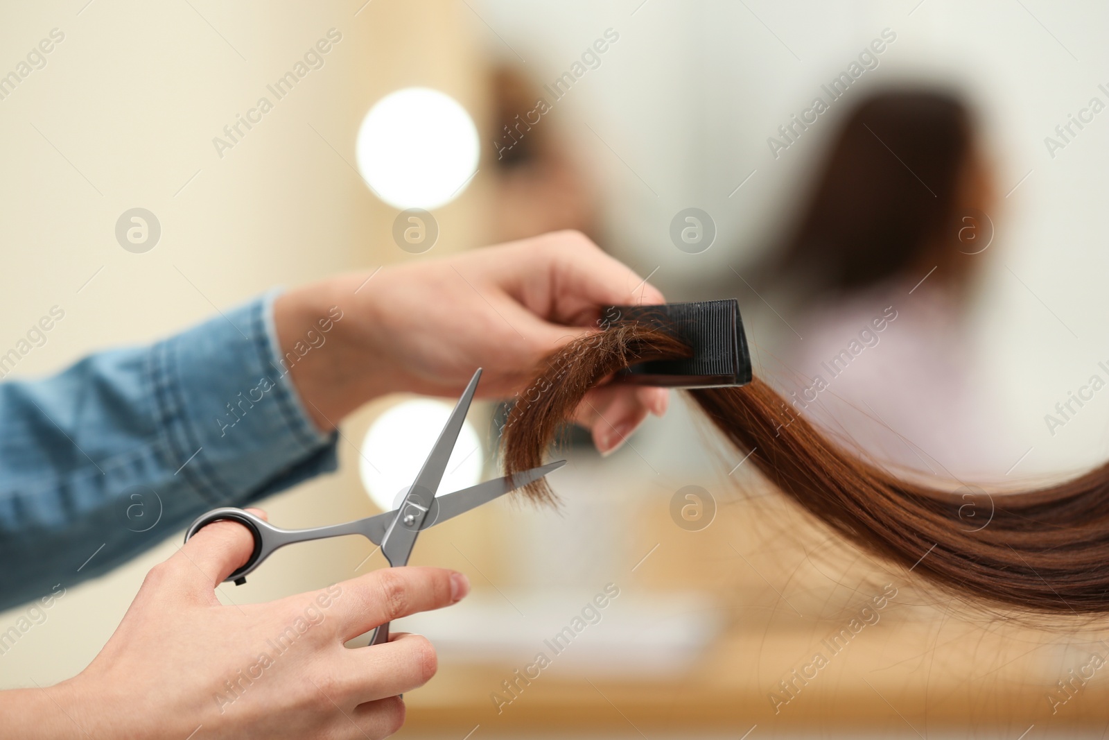 Photo of Barber making stylish haircut with professional scissors in beauty salon, closeup