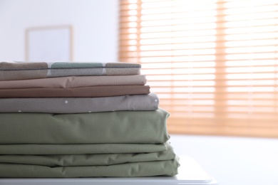 Photo of New clean folded bed linens on table indoors. Space for text