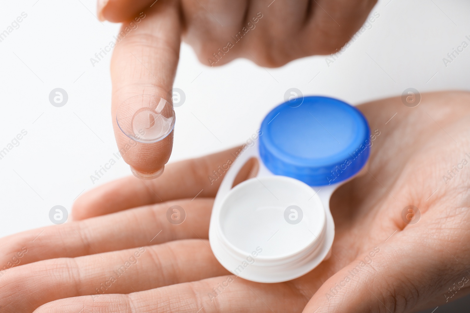 Photo of Woman holding case with contact lenses on white background, closeup