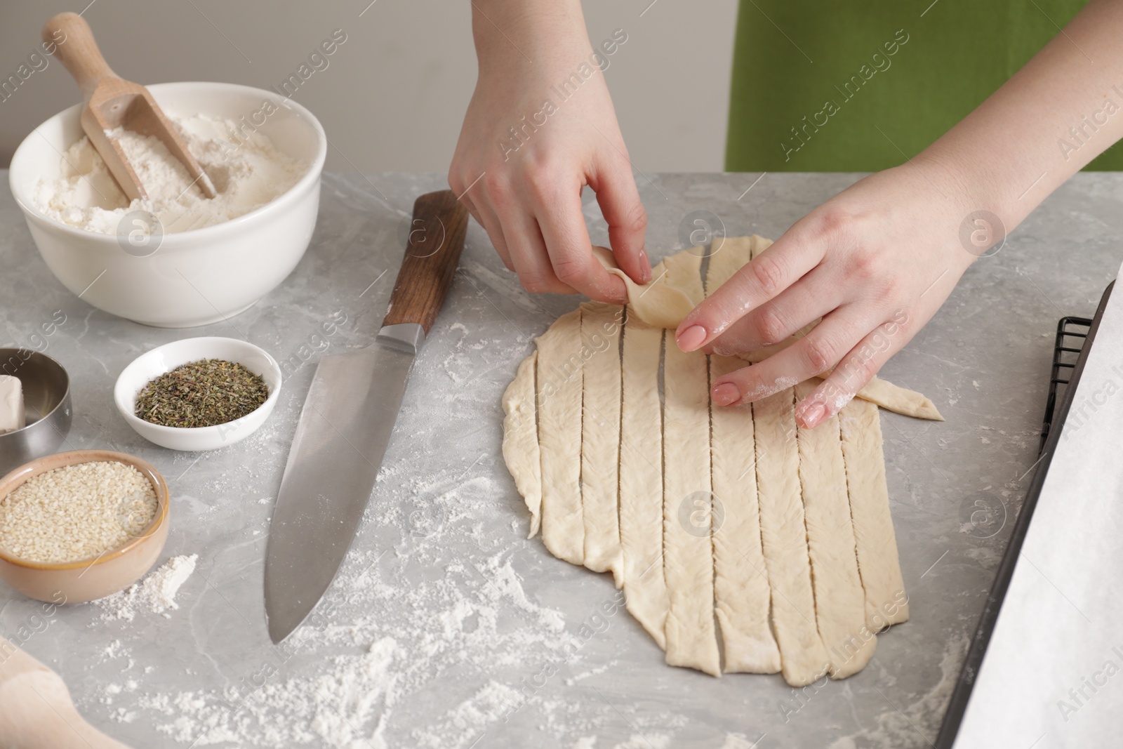 Photo of Woman making grissini at light grey marble table, closeup