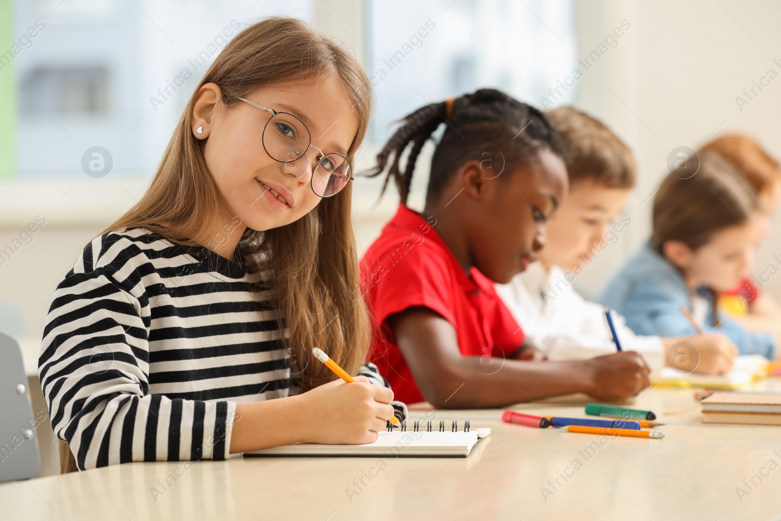 Photo of Smiling girl with her classmates studying in classroom at school