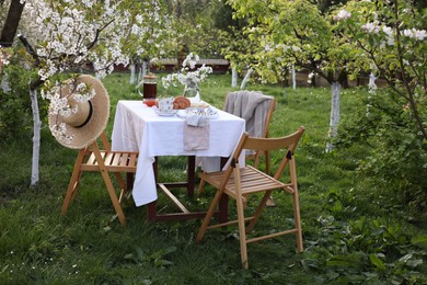 Stylish table setting with beautiful spring flowers, tea and croissants in garden