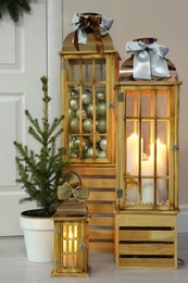 Photo of Beautiful Christmas lanterns and fir tree near entrance indoors