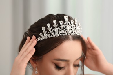 Photo of Beautiful young woman wearing luxurious tiara on blurred, closeup