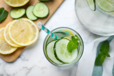 Photo of Refreshing water with cucumber, lemon and mint on white marble table, flat lay