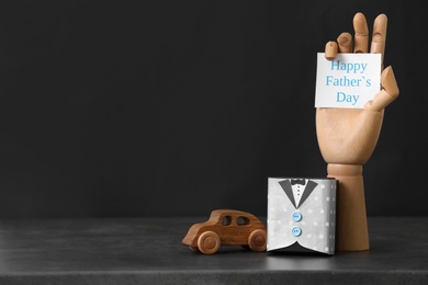 Photo of Gift box, toy car and wooden hand on table. Father's day celebration