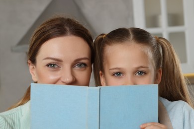 Photo of Woman and her daughter with recipe book in kitchen, closeup