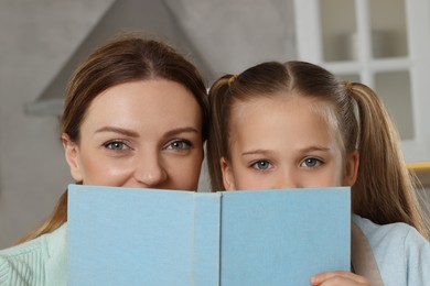 Woman and her daughter with recipe book in kitchen, closeup