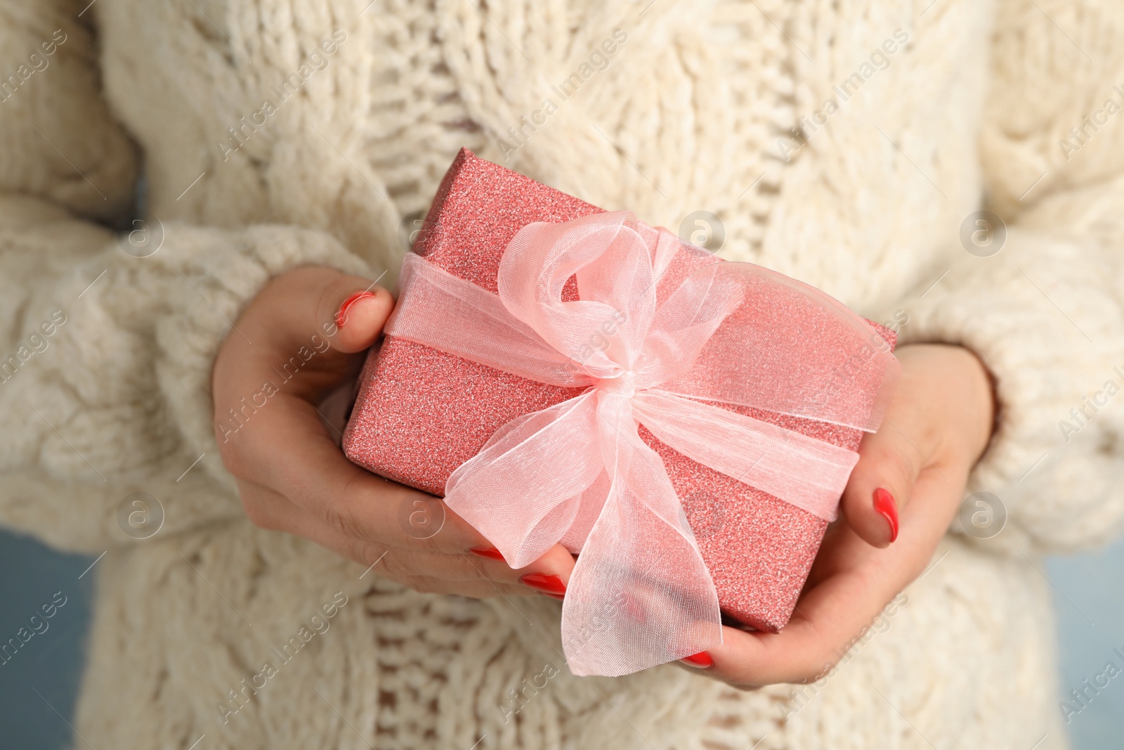 Photo of Young woman holding Christmas gift, closeup view