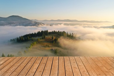 Image of Empty wooden surface, beautiful landscape with thick mist and forest in mountains