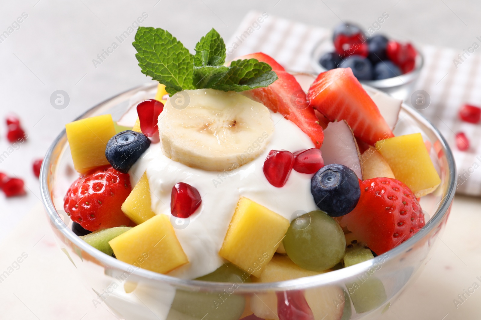 Photo of Delicious fruit salad with yogurt in bowl on table, closeup