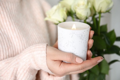 Photo of Woman holding burning candle with wooden wick, closeup