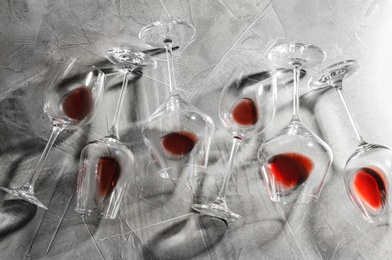 Photo of Different glasses with red wine on grey background, flat lay