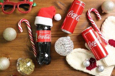 Photo of MYKOLAIV, UKRAINE - January 01, 2021: Flat lay composition with Coca-Cola drinks and Christmas decorations on wooden background