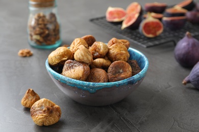 Photo of Bowl with delicious dried figs on grey table. Organic snack