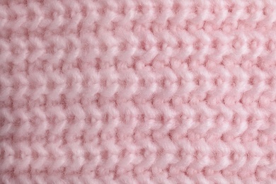 Pink knitted sweater as background, closeup view