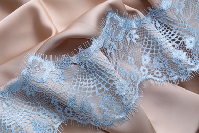 Photo of Beautiful light blue lace on beige fabric, top view