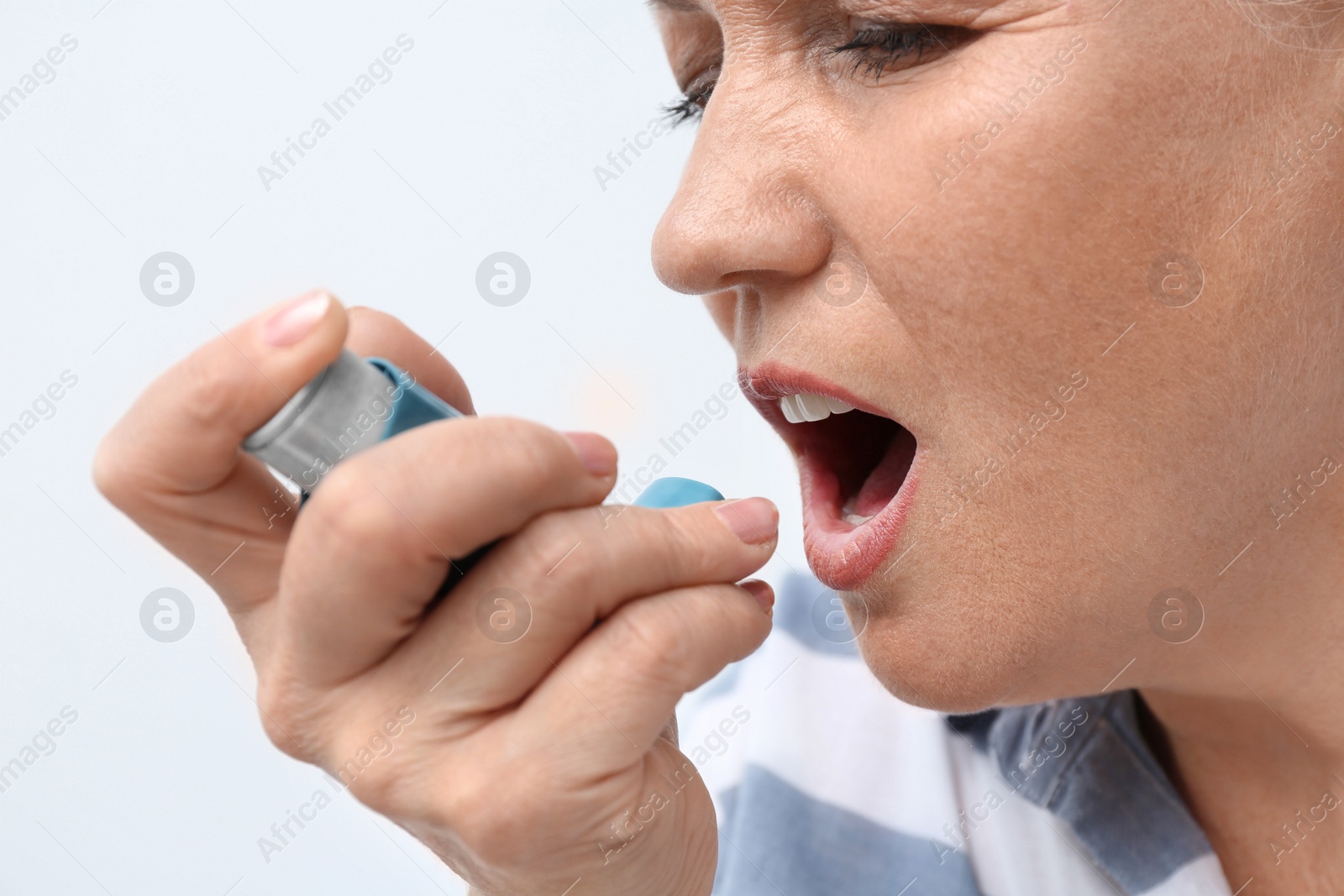 Photo of Woman using asthma inhaler on white background, closeup
