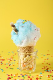 Photo of Sweet cotton candy in waffle cone on yellow background, closeup