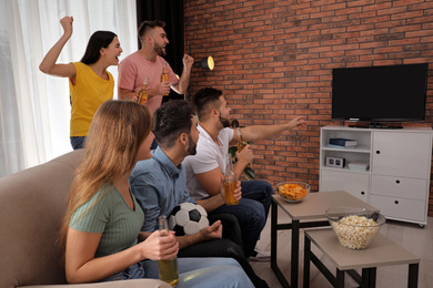 Group of friends watching football at home