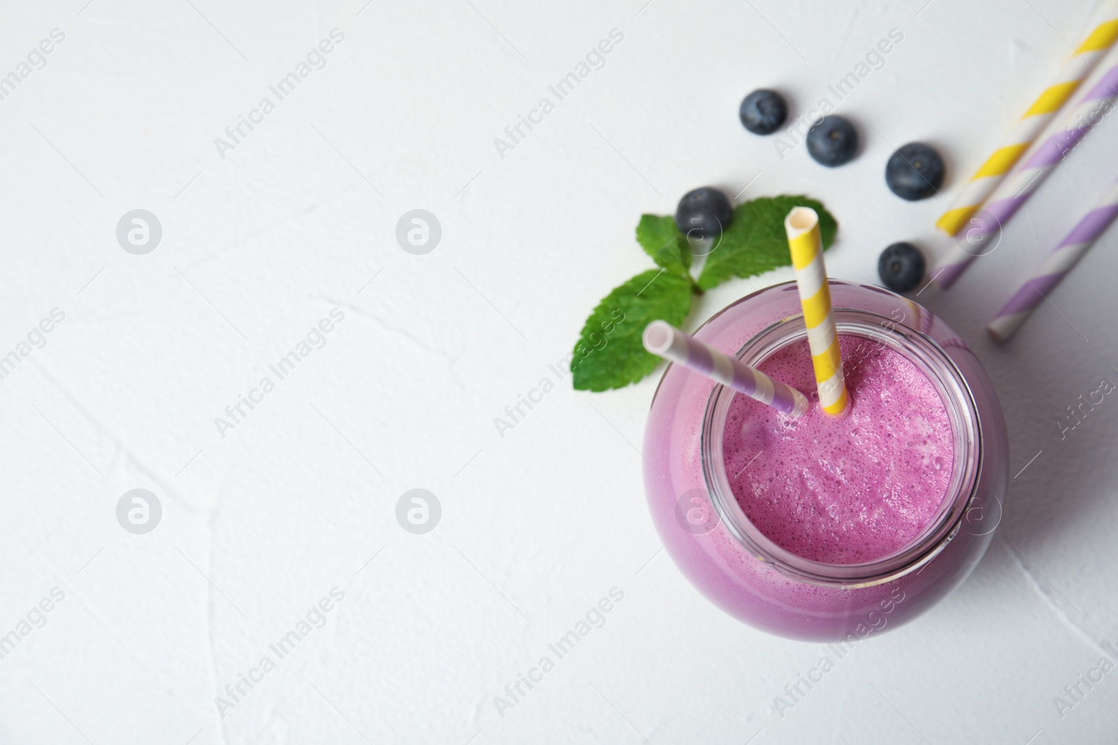 Photo of Jar of tasty milk shake and space for text on light background, top view