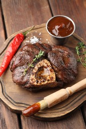 Photo of Delicious roasted beef meat served with sauce and spices on wooden table
