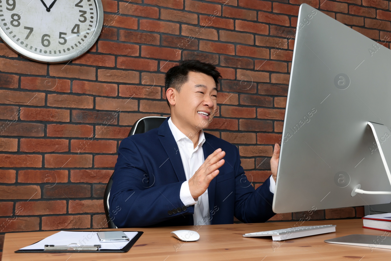 Photo of Happy boss having online meeting via computer at wooden table in modern office