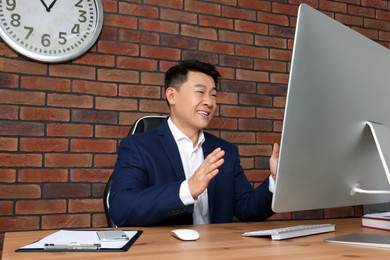 Photo of Happy boss having online meeting via computer at wooden table in modern office