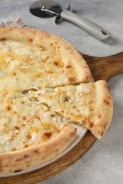 Delicious cheese pizza and cutter on light grey table, closeup