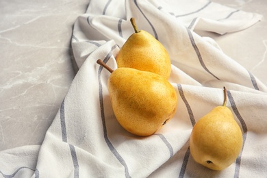 Photo of Ripe pears and striped fabric on grey table