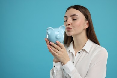 Photo of Woman with piggy bank on light blue background, space for text