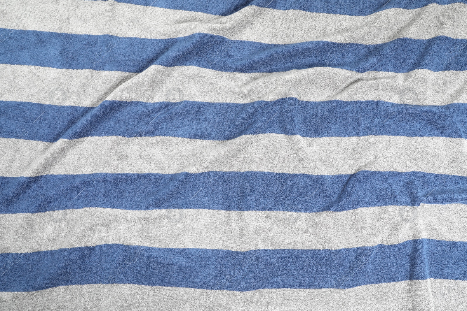 Photo of Crumpled striped beach towel as background, top view