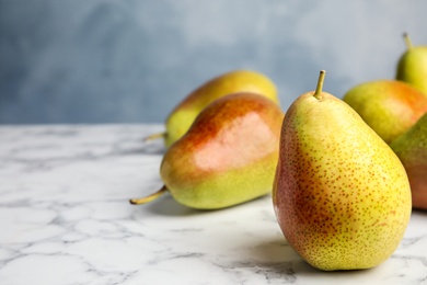 Ripe juicy pears on marble table against blue background. Space for text