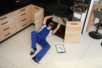 Photo of Male plumber repairing kitchen sink, above view