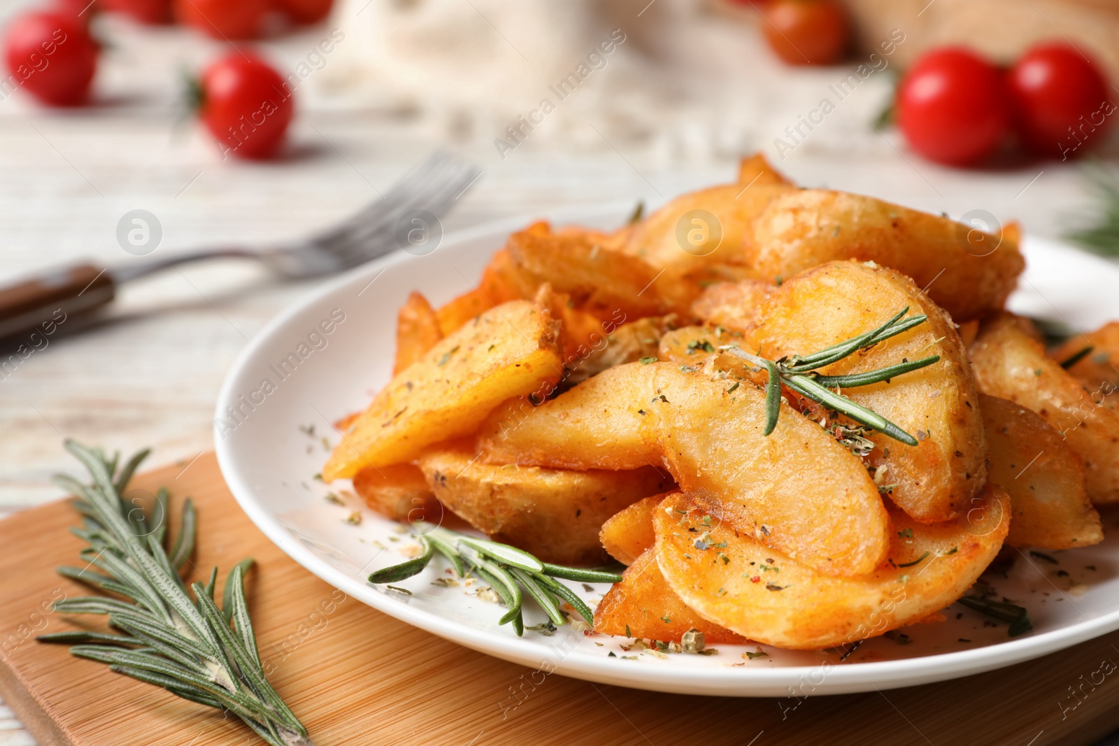 Photo of Plate with tasty baked potatoes and rosemary on wooden board