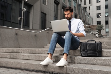 Photo of Handsome man working with laptop on city street