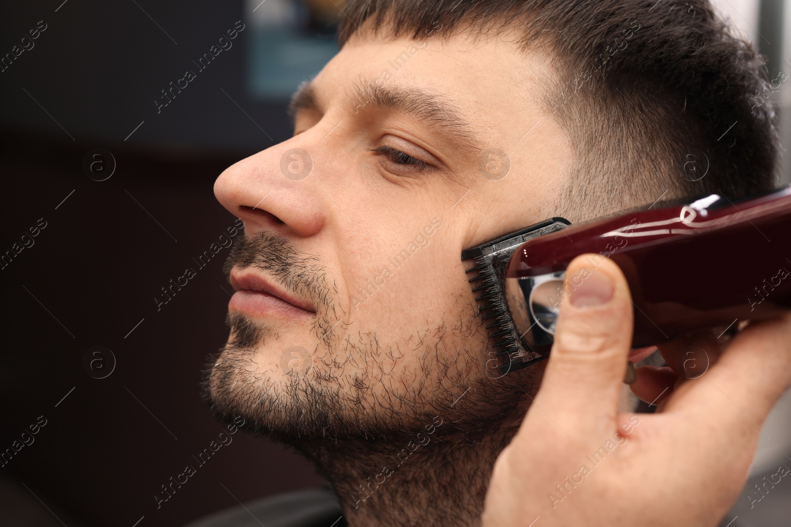 Photo of Professional hairdresser working with client in barbershop, closeup