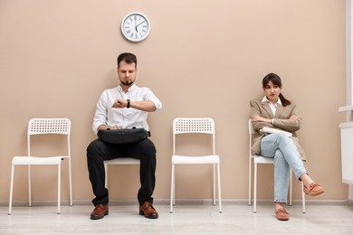 Man and woman waiting for job interview indoors