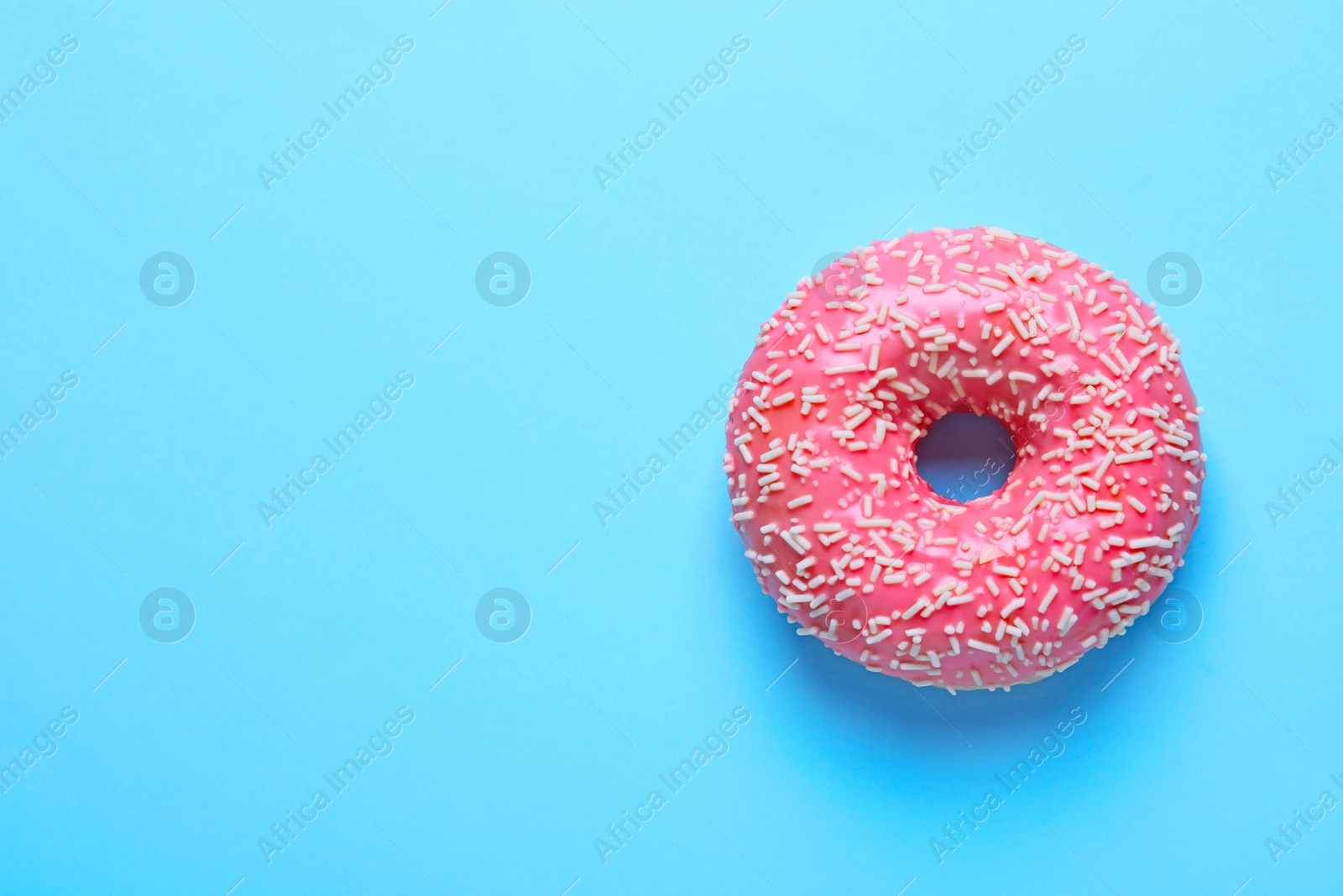 Photo of Delicious glazed doughnut with sprinkles on color background, top view