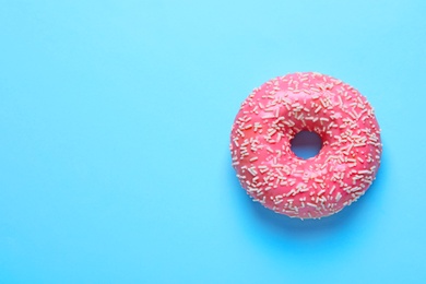 Photo of Delicious glazed doughnut with sprinkles on color background, top view