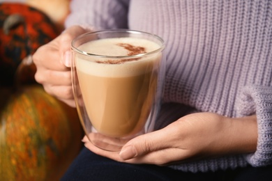 Woman holding glass cup with pumpkin spice latte, closeup